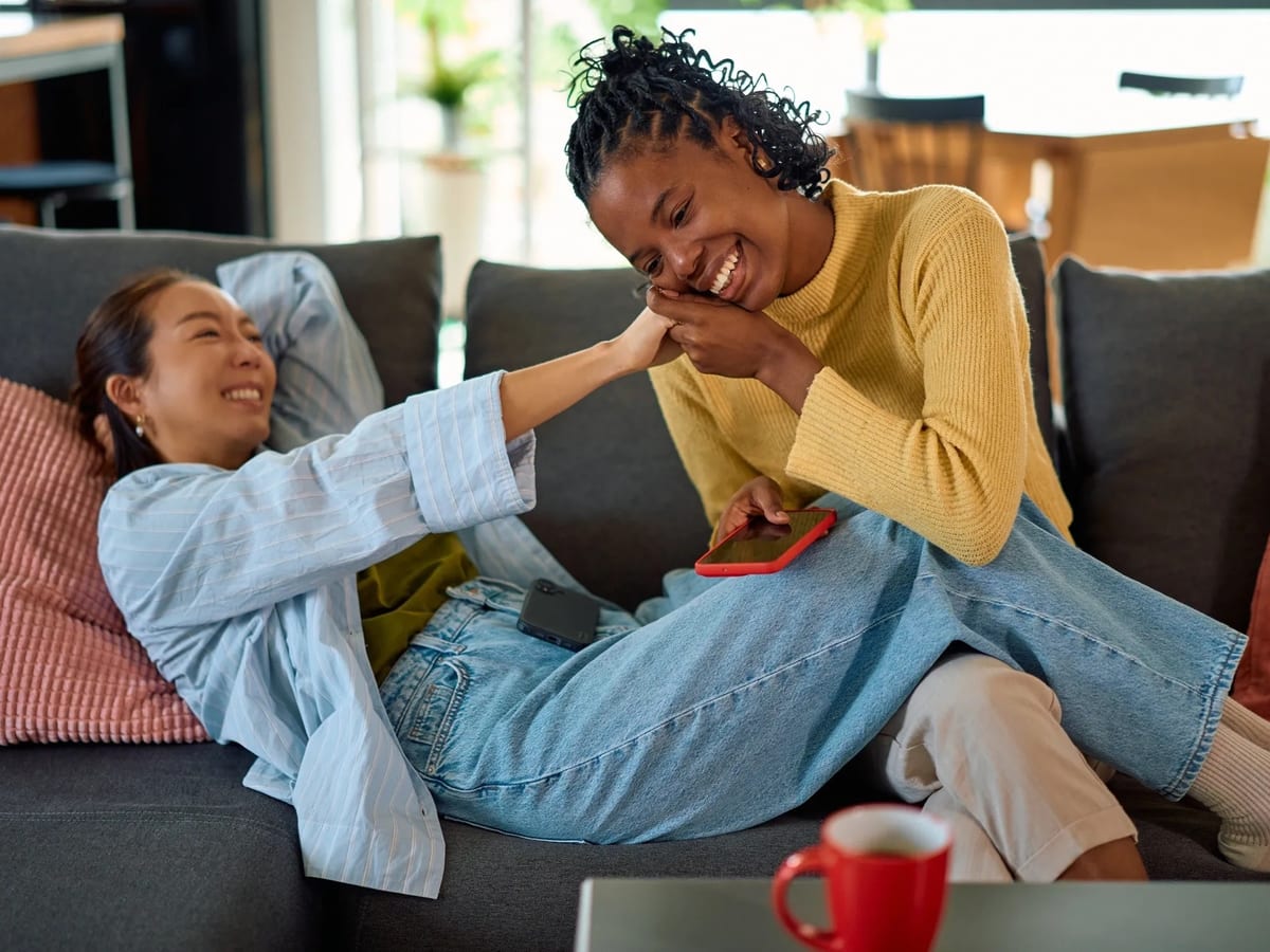 Two women laughing together on a couch
